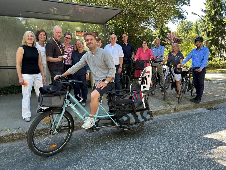Mitarbeitende des Ökumenewerks vor einer Bushaltestelle mit Fahrrädern 