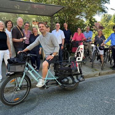 Mitarbeitende des Ökumenewerks vor einer Bushaltestelle mit Fahrrädern Mitarbeitende des Ökumenewerks der Nordkirche vor Bushäuschen zur Präsentation des Mobilitätskonzepts