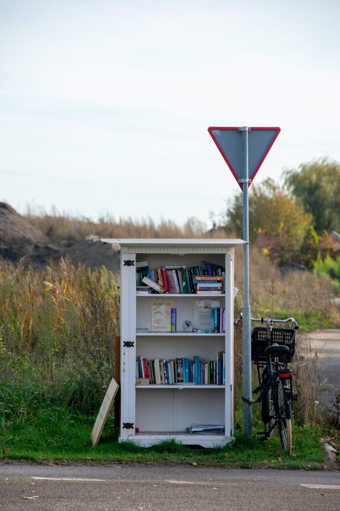 Tauschbox mit Büchern an Landstraße. Radpilgern führt zu den schönsten Orten der Natur und verbindet klimaschonendes Reisen mit Spiritualität