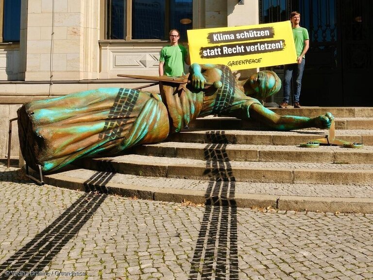 Mit einer vier Meter großen, von Reifenspuren überfahrenen Justitia-Figur protestierten Greenpeace-Aktivist:innen am Montagmorgen vor dem Eingang des Verkehrsministeriums gegen die Klimapolitik der Bundesregierung.